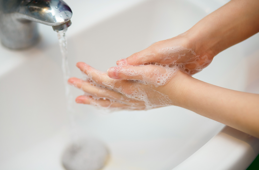 Close up of young hands being washed with soap.